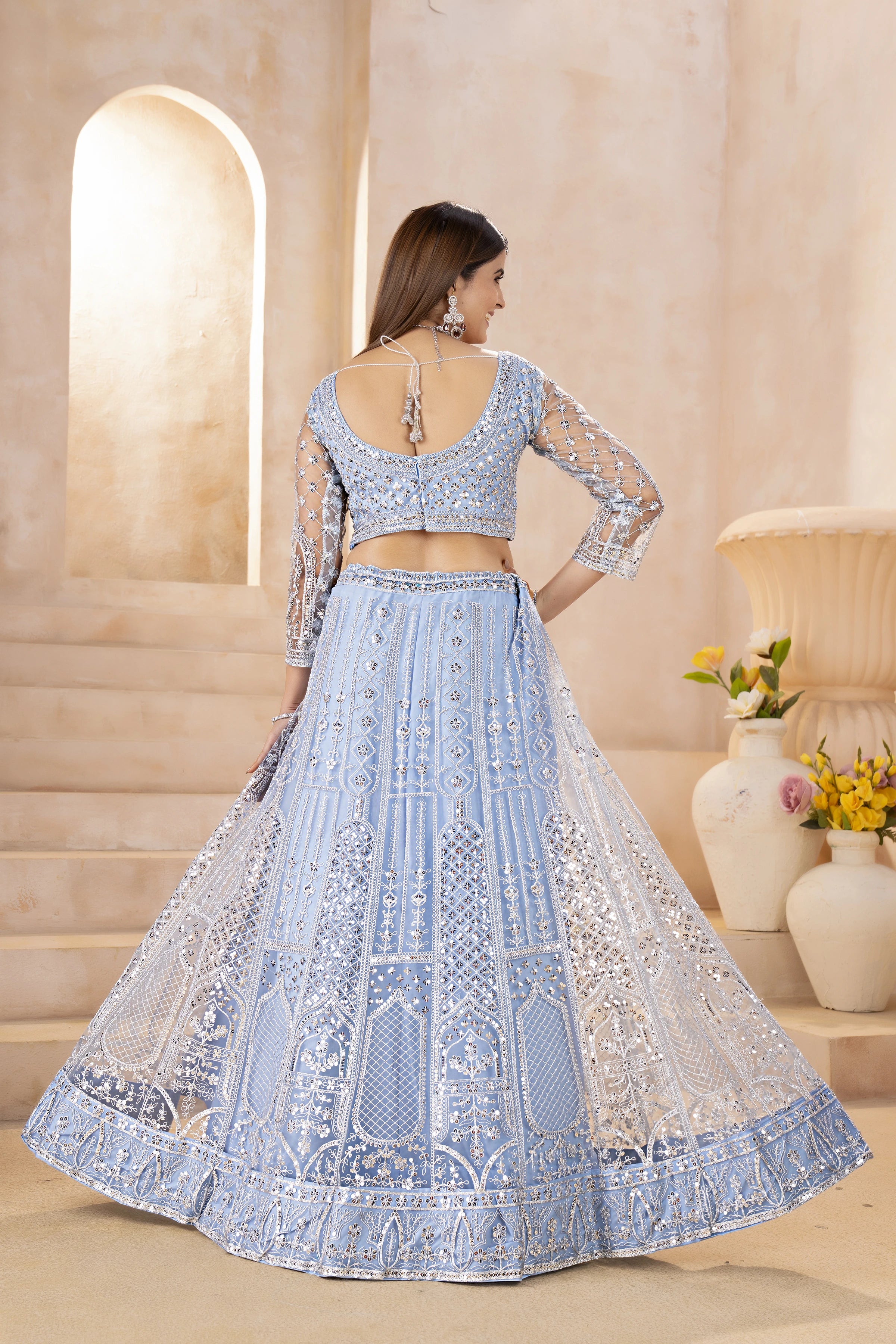 Woman wearing a light blue embroidered lehenga in an elegant indoor setting.